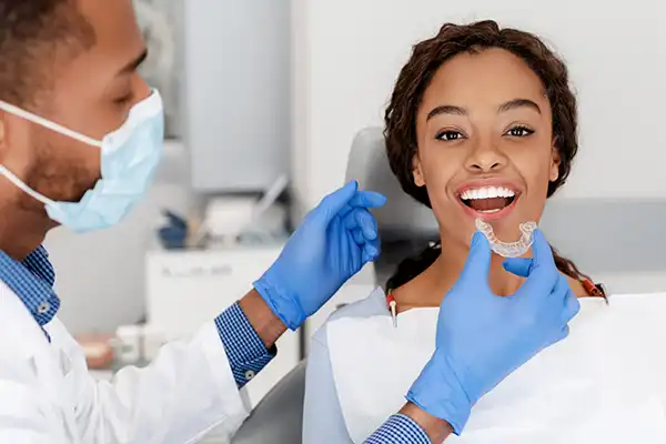 Doctor holding Invisalign clear aligners in front of patient sitting in dental chair