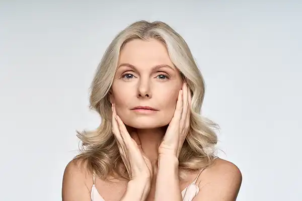 Adult senior older woman touching her perfect skin while looking at camera