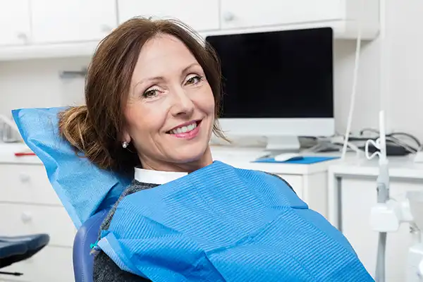 Smiling dental patient sitting in exam chair and looking at camera