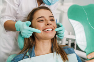 Young woman smiling while looking at mirror in dental clinic, showing off her porcelain veneers