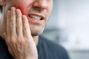 Man holding his jaw in pain from untreated TMJ disorder